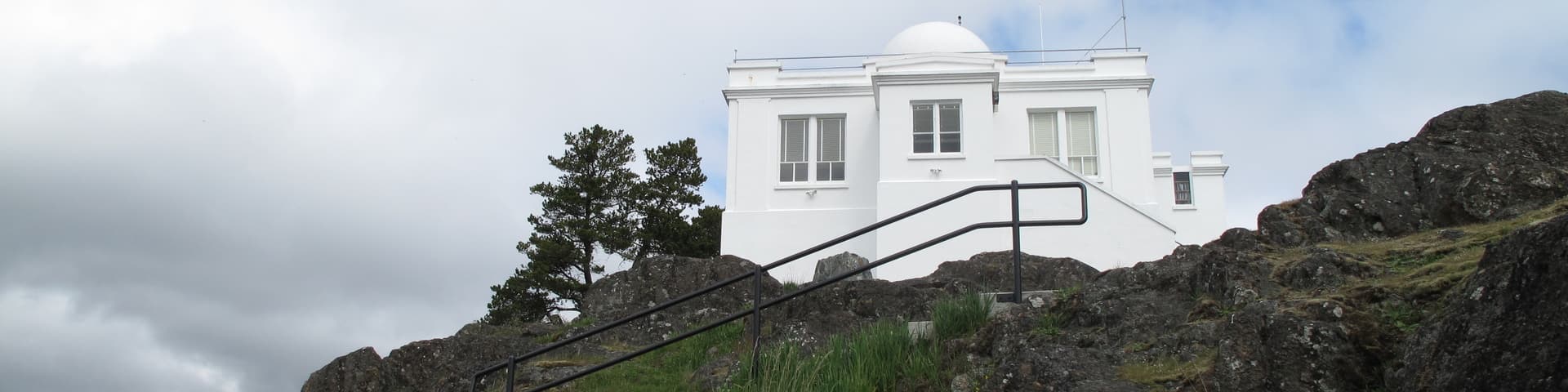 A white observatory with a big dome on a rocky hill.